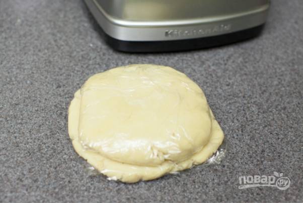 Достаньте тесто и быстро вымесите руками, затем разделите на 2 куска, заверните в целлофан и отправьте в холодильник минимум на 15 минут.