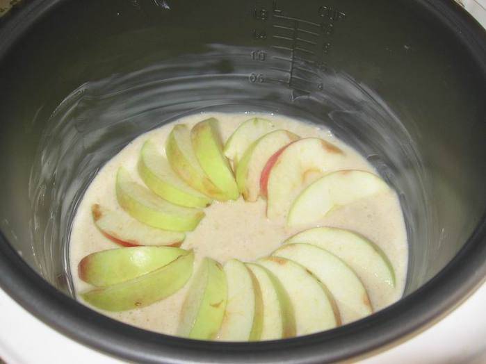 Чашу мультиварки смазать маслом и вылить тесто. Сверху уложить яблоки порезанные дольками.