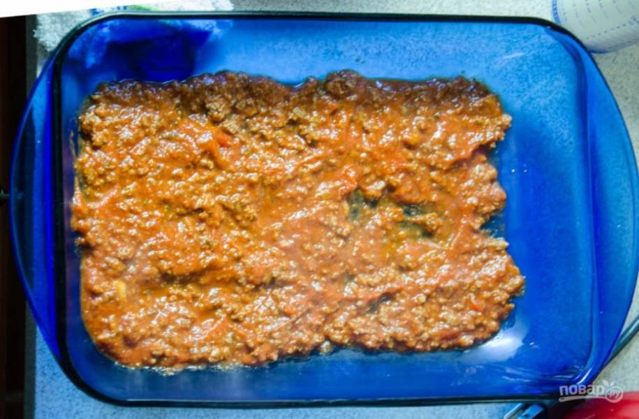 Сделайте смесь из фарша, томатного соуса, чеснока, соли, перца, итальянских трав и орегано. Выложите часть массы первым слоем на дно жаропрочной формы.