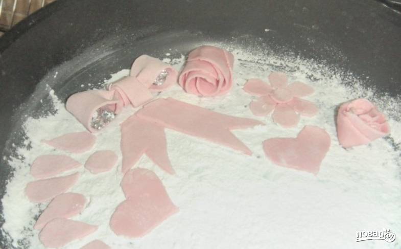 Из розовой мастики можно вырезать любые украшения для торта. Затем поместить их в холодильник на 5 часов.