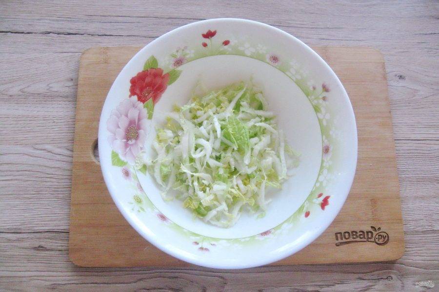 Нашинкуйте или тонко нарежьте пекинскую капусту. Выложите в салатник.