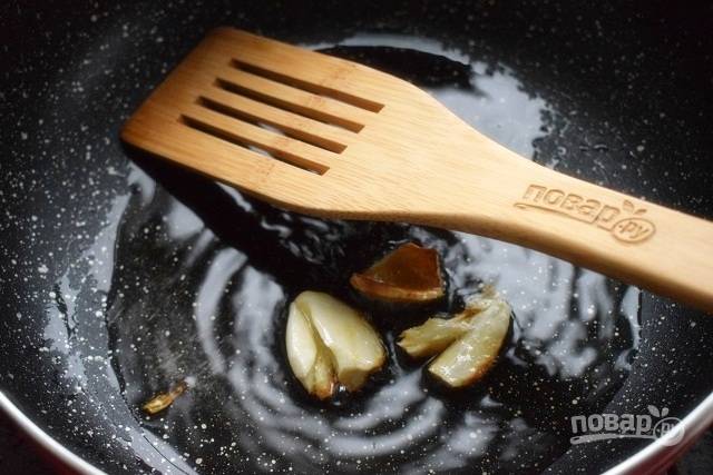В воке или большой сковороде с антипригарным покрытием разогрейте растительное масло и обжарьте раздавленный чеснок и имбирь. Уберите коренья со сковороды.