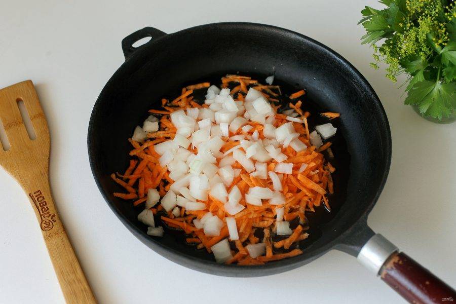 В сковороде разогрейте масло и выложите нарезанный кубиками лук и тертую морковь.