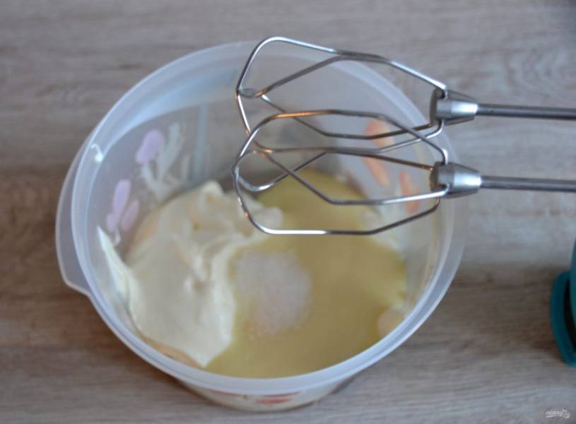 Для приготовления сметанного крема взбейте сметану и сгущенное молоко, они должны быть охлажденными, из холодильника. Добавьте в массу ванильный сахар. 