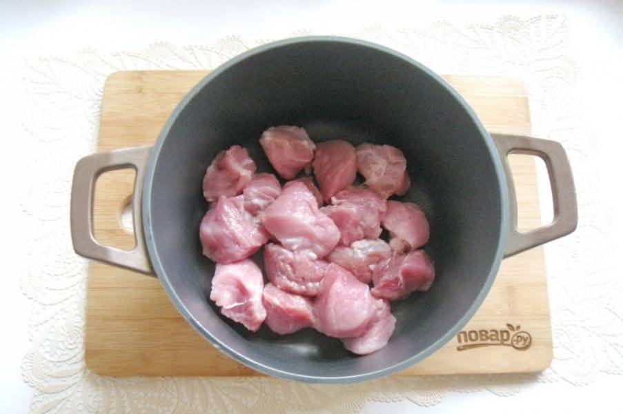 Мякоть свинины помойте, нарежьте небольшими кусочками и выложите в казан или кастрюлю с толстым дном.
