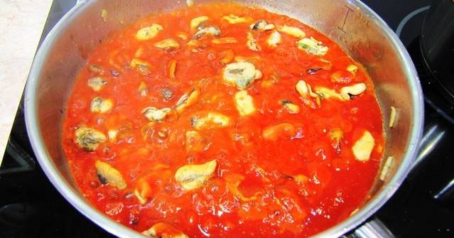2. Когда лишняя жидкость уйдет, а мидии немного потемнеют - вливаем томаты в собственном соку. Можно взять просто измельченные помидоры, а можно взять томатный сок. Доводим до кипения на маленьком огне, добавим специи, выключаем.