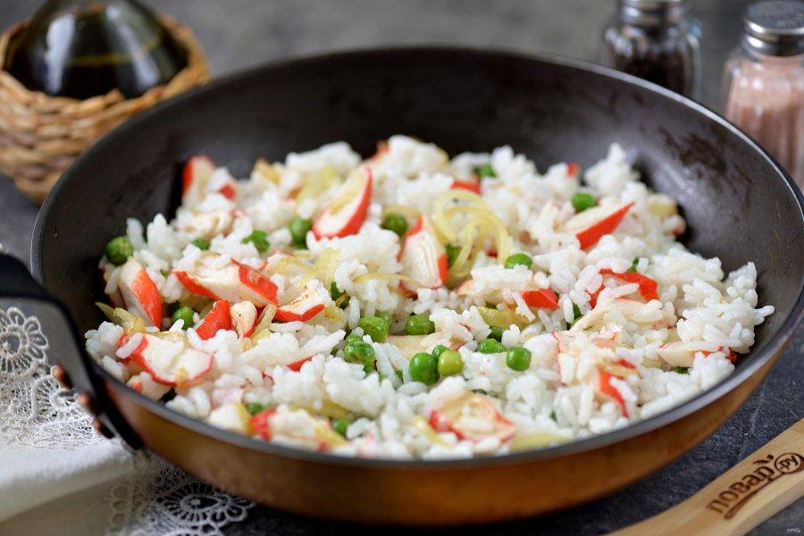 Добавьте в сковороду вареный рис, тщательно перемешайте, прогрейте минуты две, посолите и поперчите по своему вкусу. 