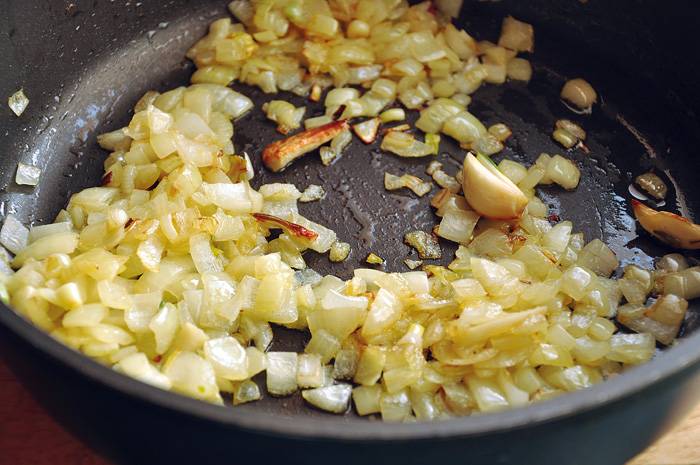 7. Разогреть на сковороде немного растительного масла. Выложить туда измельченный лук и обжарить до золотистого цвета. Чеснок можно тоже нарезать или добавить на сковороду целиком, просто для аромата. 