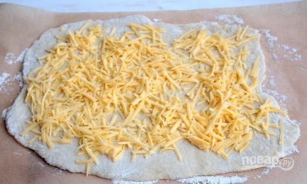 Тесто раскатайте в пласт. Сверху рассыпьте сыр и базилик.