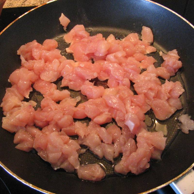 Нарезать филе курицы маленькими кубиками. Выложить на разогретую сковороду с маслом. Жарить на среднем огне 10-15 минут.