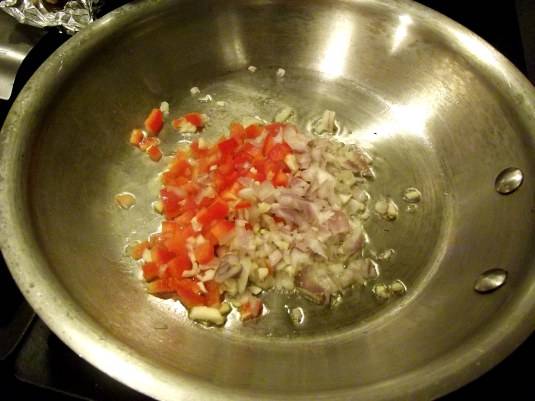 2. На разогретую сковороду добавьте немного растительного масла и выложите порезанный полукольцами репчатый лук и нарезанный кубиками сладкий перец. Обжаривайте примерно в течение 5-7 минут на среднем огне, постоянно помешивая.
