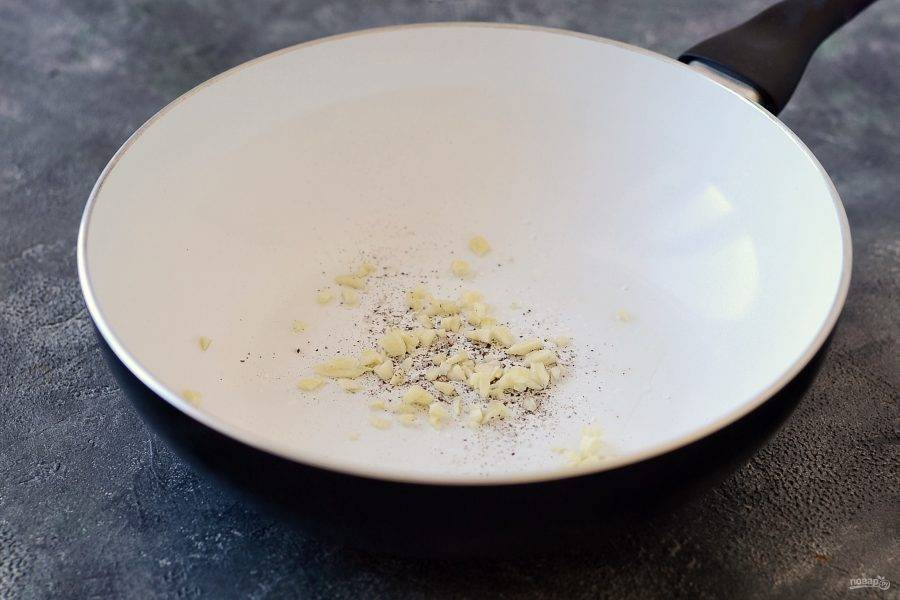 Разогрейте сковороду с маслом. Добавьте соль, перец и мелко рубленый чеснок. Обжарьте 20-30 секунд до раскрытия аромата.