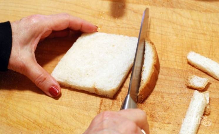1.	Возьмите мягкий хлеб (лучше для тостов), можно нарезанный тонко, или купите целую булку и нарежьте тонко сами. Обрежьте все корочки.