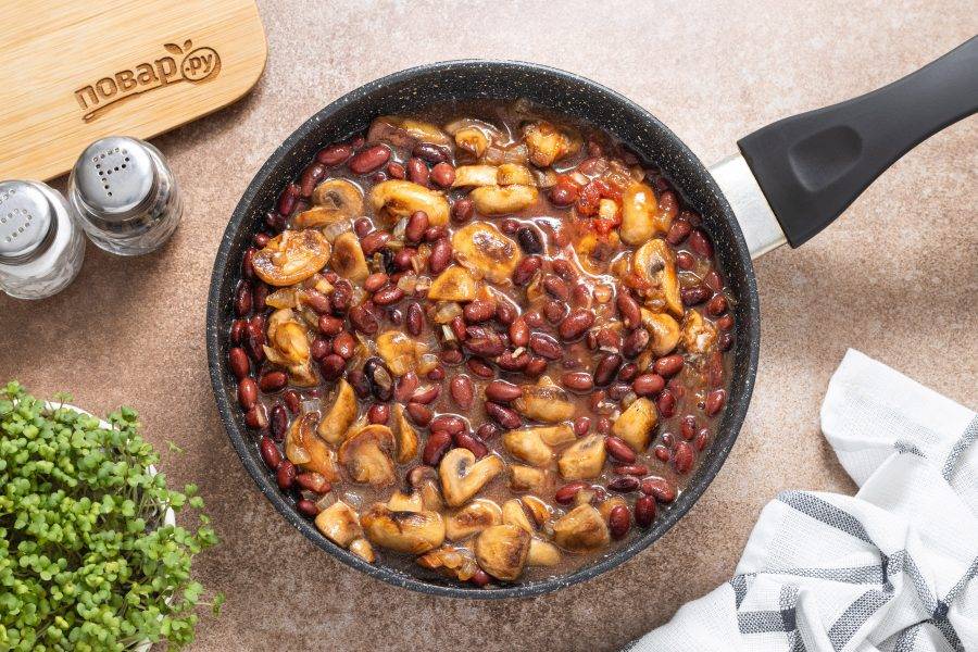 Накройте сковороду крышкой и томите фасоль с шампиньонами на небольшом огне около 15-20 минут. Периодически помешивайте. Если вода выпарится раньше времени, то можно подлить еще.