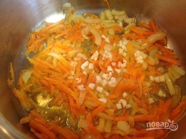 2. Очистим лук и морковь. Лук нарезаем четвертькольцами, морковь натираем на крупной терке. Обжариваем до мягкости на растительном масле. Добавим мелко нарезанный чеснок и обжариваем еще минуту.
