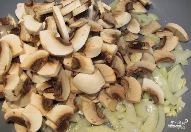 Расколите на сковороде оливковое масло, выложите грибы, рубленный чеснок и лук. Обжаривайте всё вместе 8-10 минут.