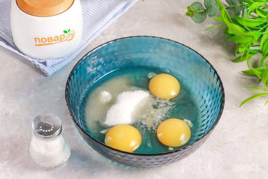 Вбейте куриные яйца в глубокую емкость, всыпьте 1 ст.л. сахара и соль, взбейте все венчиком примерно 1-2 минуты.