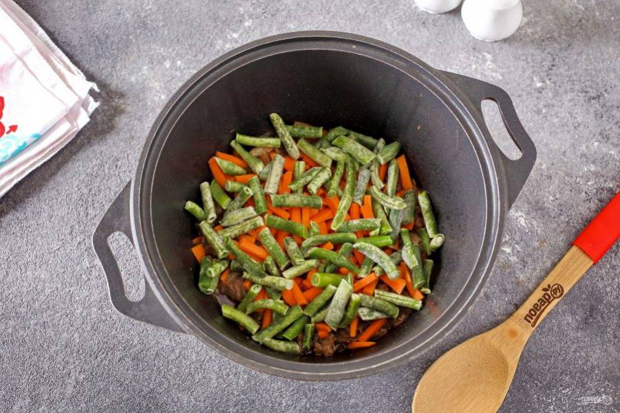 Добавьте нарезанную соломкой морковь и стручковую фасоль. Продолжайте тушить еще 5-7 минут.