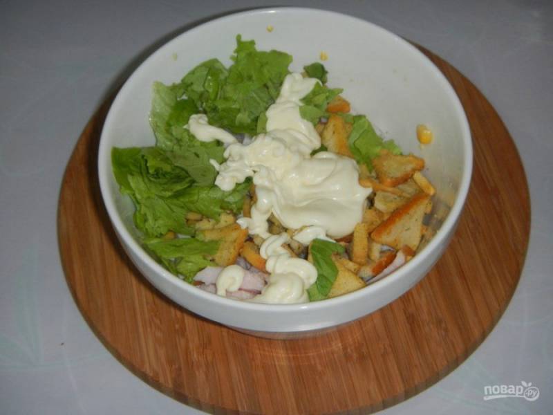 В салат добавьте порванные листья салата, сухарики и майонез. По вкусу посолите и поперчите.