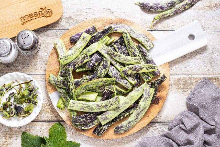 Фасоль хорошо промойте, отрежьте хвостики с двух сторон. Разрежьте на 2-4 части. Зубчики чеснока очистите от шелухи.