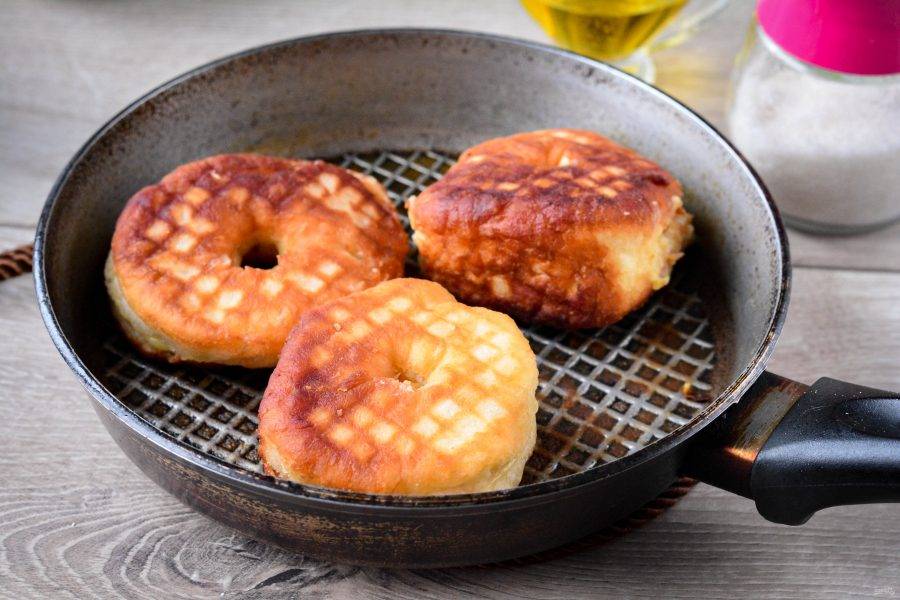 Обжаривайте пончики с двух сторон, постоянно подливая растительное масло на сковороду.