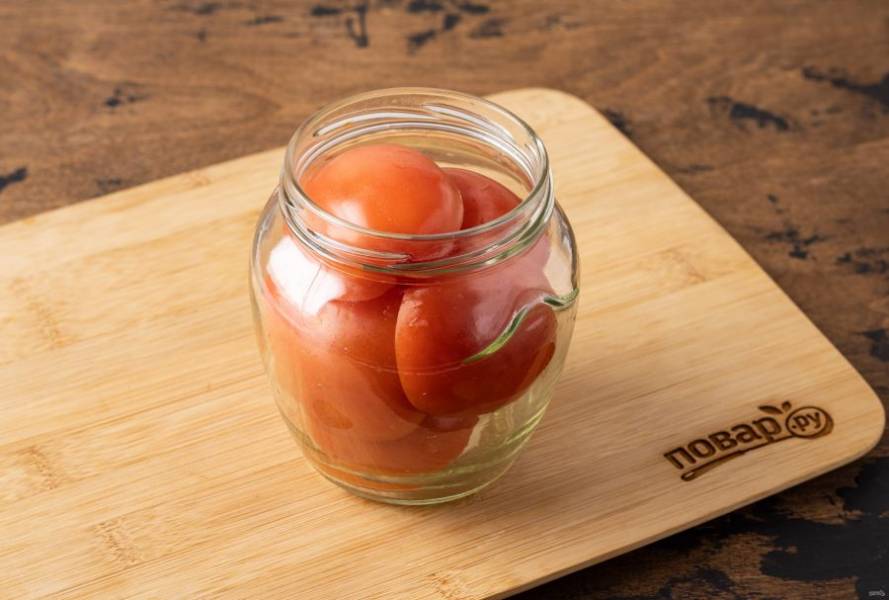 Плотно заполните банку помидорами, укладывая их срезом вниз.