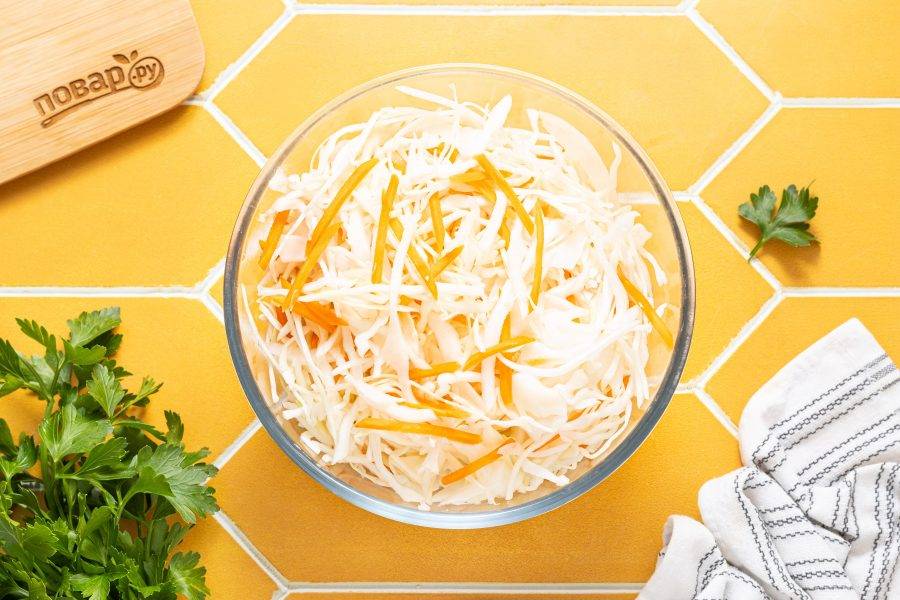 Объедините морковь с капустой в глубокой миске.