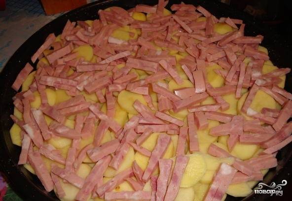 4. На картофель выложите кусочки ветчины.  Ветчину покройте слоем лука. В качестве следующего слоя используйте натертый на крупную терку сыр. 