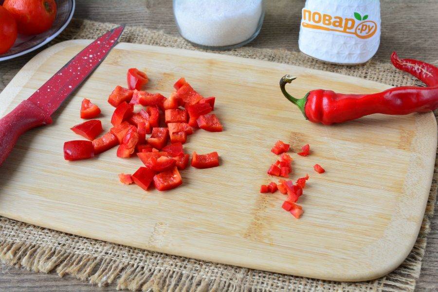 Почистите перцы. Нарежьте средними кусочками сладкий перец, острый перец, нарежьте мелкими кубиками. С перцами томатный соус получится более ароматным.