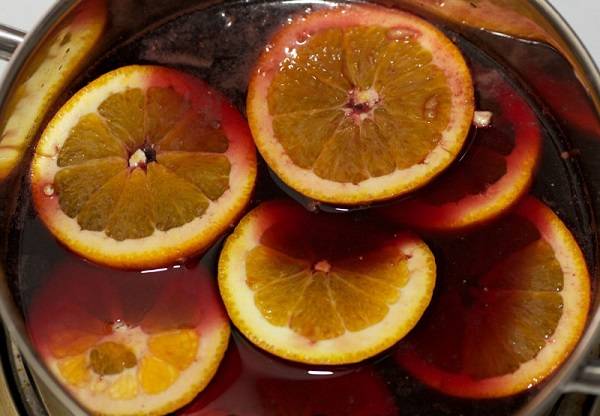 7. Отправить апельсины в кастрюлю. Нагреть глинтвейн немного, но не доводить до кипения. 