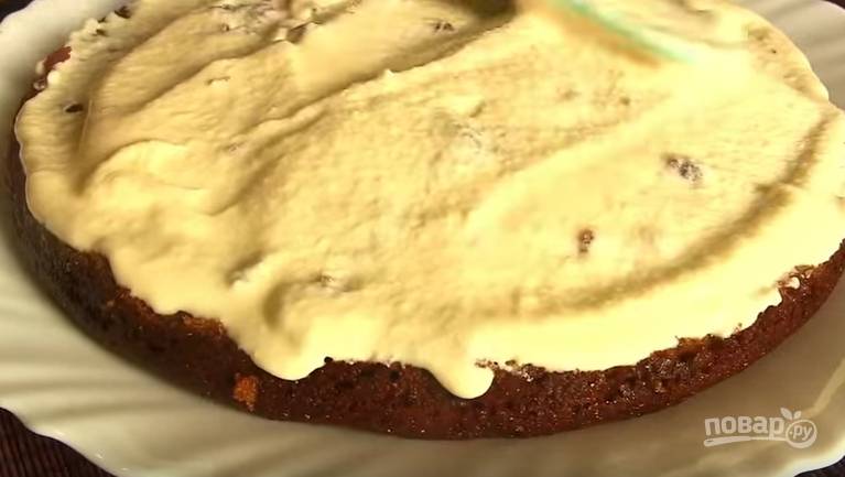 7. Когда бисквит полностью остыл, разрежьте его на 2 коржа. Смажьте нижний сметанным кремом, накройте второй половинкой и остатками крема смажьте верх и бока торта. 