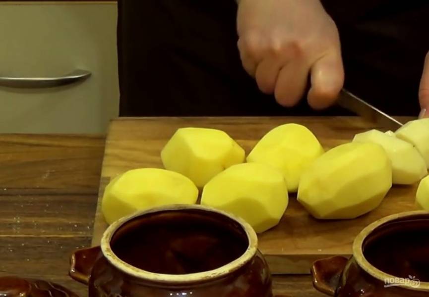 2.  Картофель очистите от кожуры и нарежьте небольшими кубиками. Сложите картофель в горшочки, посолите и залейте кипятком до половины горшочка. 