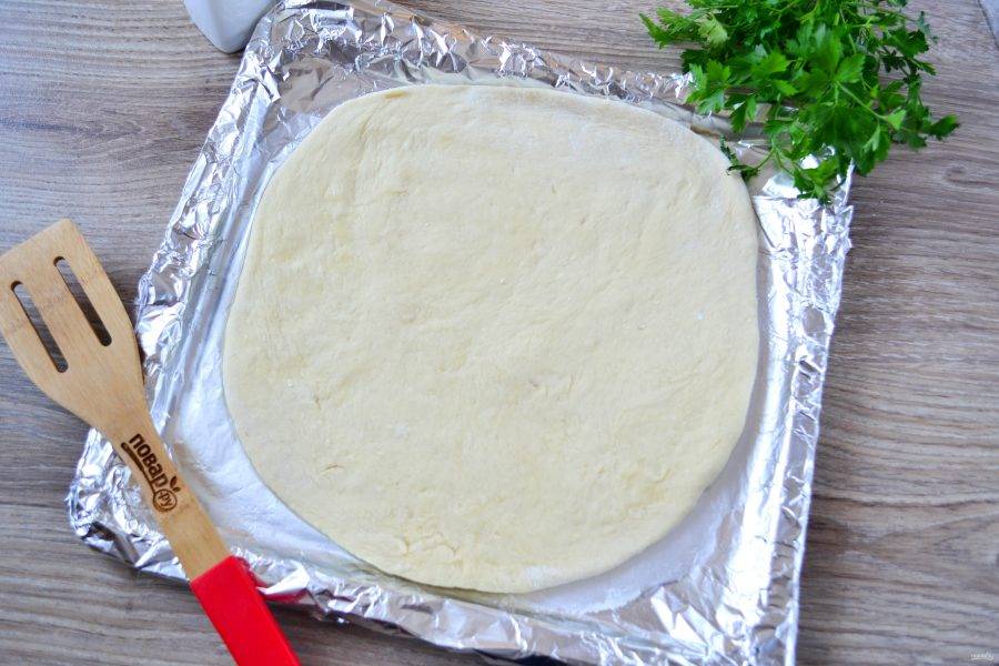 Разделите тесто на 2 неравные части. Большую часть раскатайте толщиной 5-7 мм. Переложите этот пласт теста на противень, смазанный растительным маслом. 