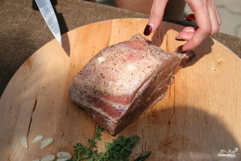 1. Для начала мясо необходимо замариновать, для этого хорошо натрите его солью, черным и красным перцем. Сделайте небольшие надрезы по всему куску и положите в них дольки чеснока.