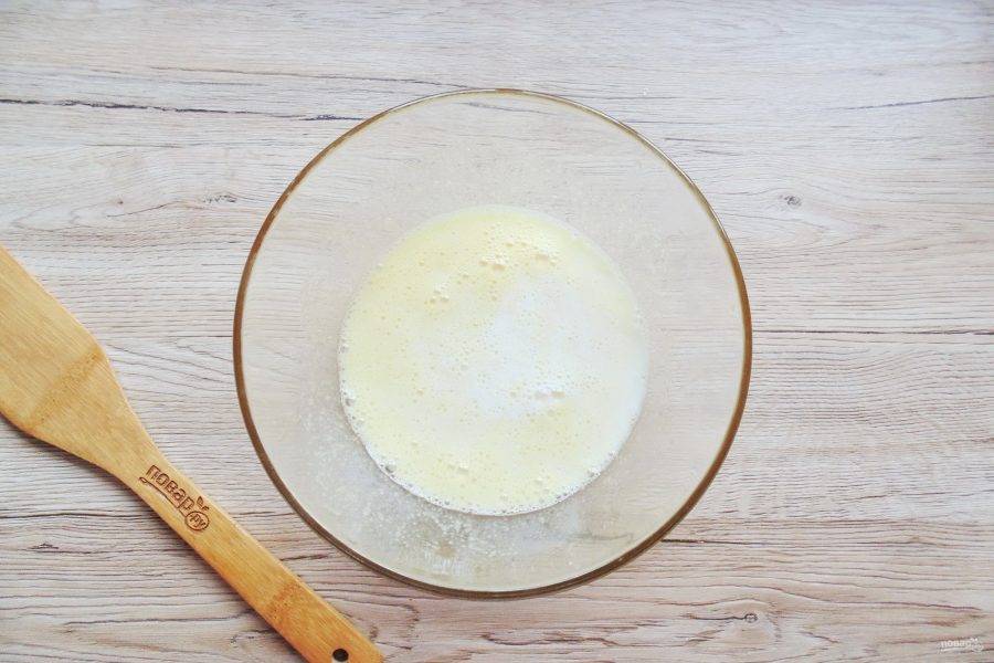 В миску разбейте яйца, добавьте сахар. Тщательно перемешайте венчиком и налейте молоко.