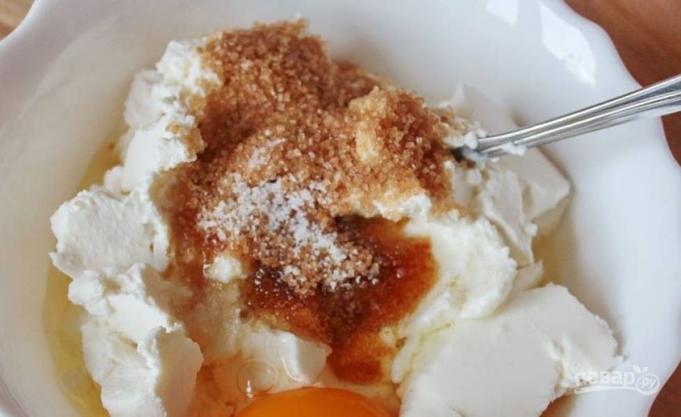 Добавьте в миску с творогом соль, сахар и вбейте сырое куриное яйцо. Тщательно все размешайте венчиком или вилкой. 