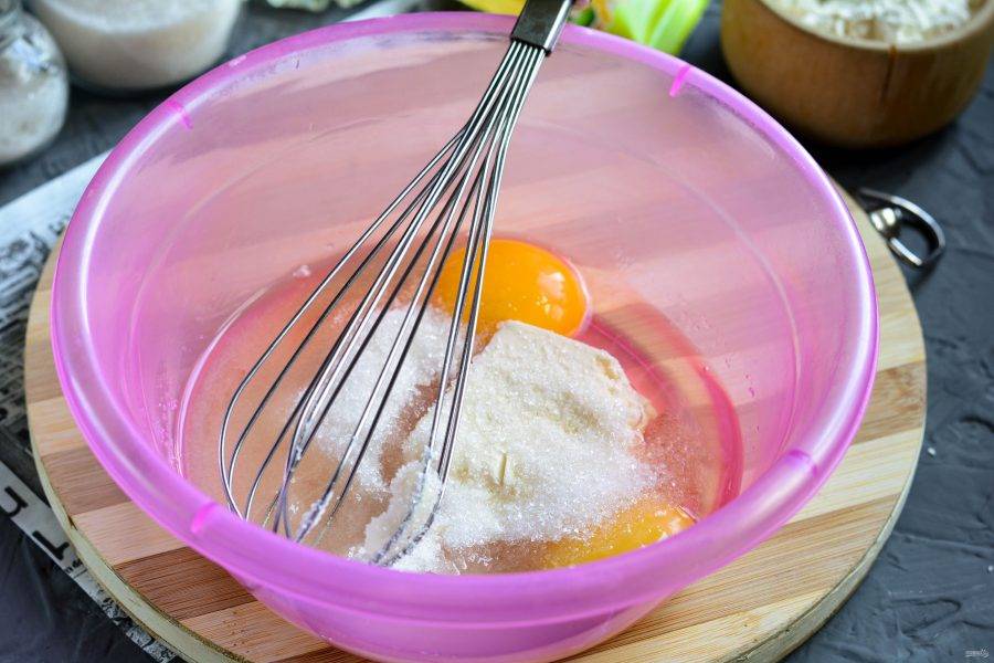 В отдельной посуде смешайте яйца, оставшийся сахар, щепотку соли, ванильный сахар и мягкое сливочное масло.