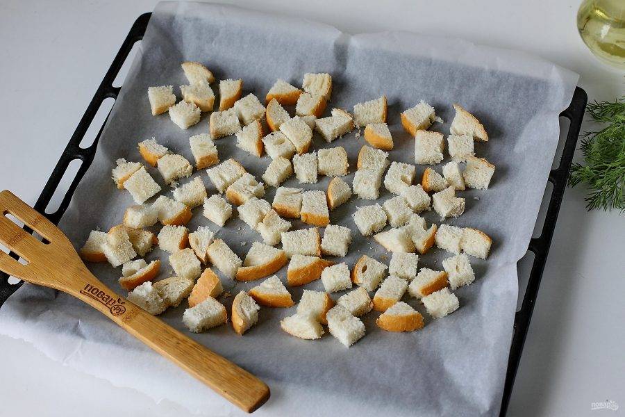 Хлеб нарежьте кубиками и переложите на противень. Подрумяньте хлеб в духовом шкафу при температуре 170-180 градусов.