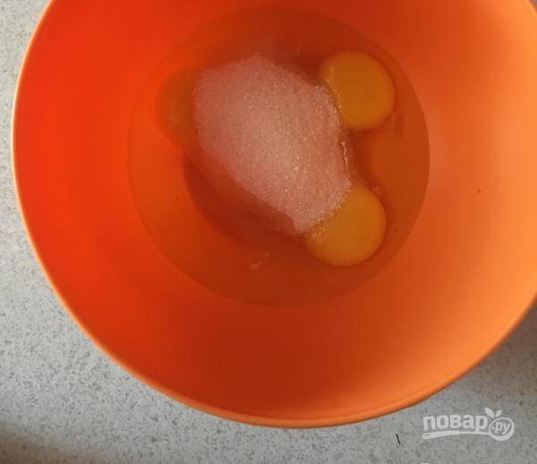 Вначале сделайте тесто для светлого коржа. Для этого в миску вбейте 3 яйца и добавьте половину сахара.