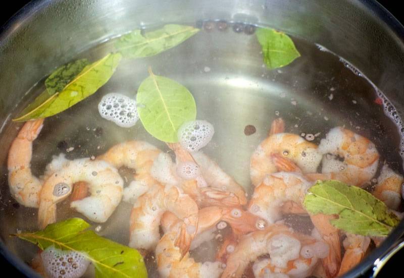2. Довести до кипения воду с лавровым листом и горошинами перца. Выложить туда замороженные креветки. Также в рецепт приготовления салата "Лагуна" можно использовать кальмары. 
