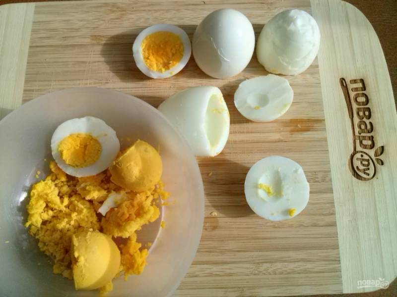 Очистите яйца от скорлупы, отрежьте 1/4 часть снизу. С помощью ложки выньте желток. 