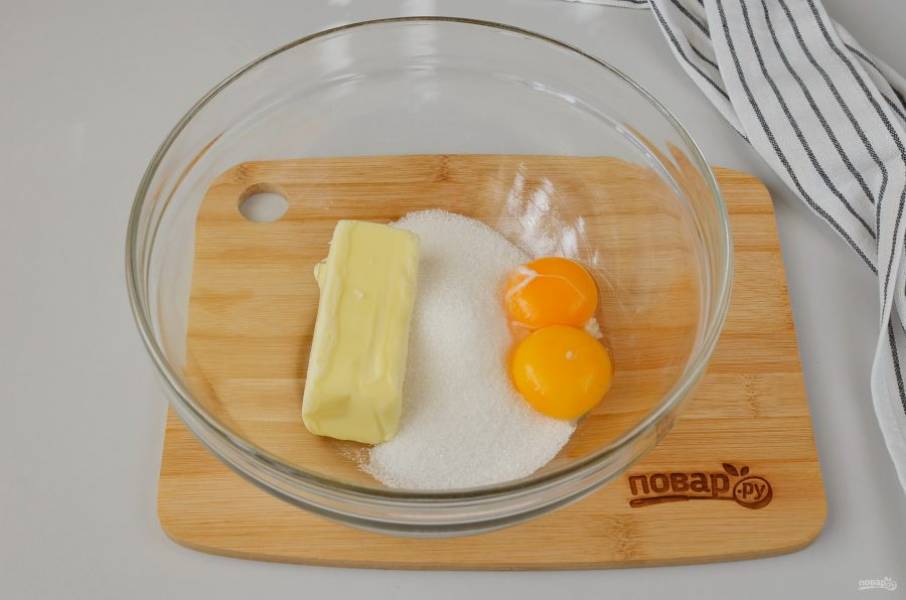 В большую миску выложите кусочек масла, поставьте в микроволновку на 20-30 секунд (или смотрите по своей микроволновке сколько понадобится времени), чтобы масло стало мягким. Добавьте два желтка и сахар. Миксером взбейте массу до однородного состояния.