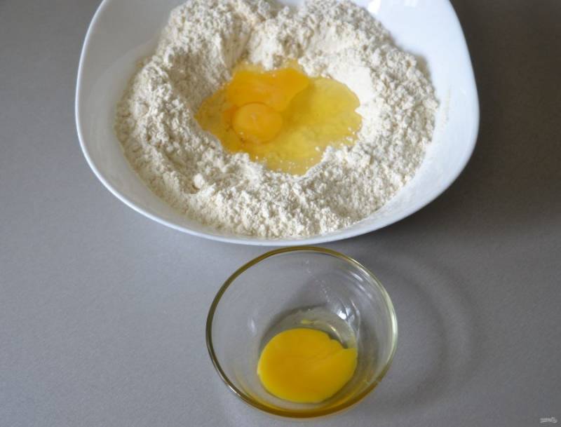 Сделайте в муке углубление, влейте полтора яйца, половинку яйца оставьте для смазки перед выпечкой.