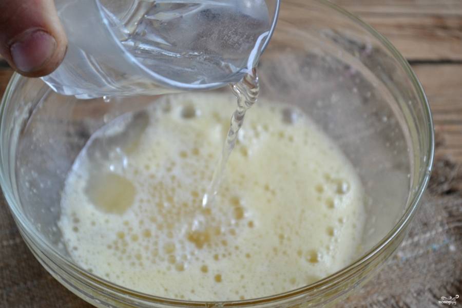 Один из секретов приготовления теста для блинов заключается в том, что яйцо нужно обязательно взбить с сахаром, как на бисквит. Тогда блины получатся очень пышными и мягкими. К яичной массе добавьте холодную воду, перемешайте.