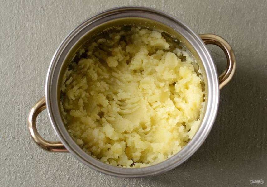Вытащите морковь, перец горошком и лавровый лист из супа. Слейте жидкость, а картофель с луком раздавите толкушкой или вилкой.