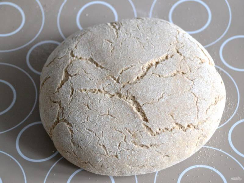 Через час разогрейте духовку до 250 градусов. Аккуратно переложите хлеб на лист для выпечки. Поверхность хлеба покрылась многочисленными трещинками.