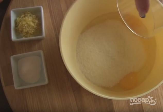 1. Разбейте яйца в емкость, добавьте сахар и взбейте миксером до пышной пены. Затем добавьте туда разрыхлитель и цедру половины лимона, перемешайте. 