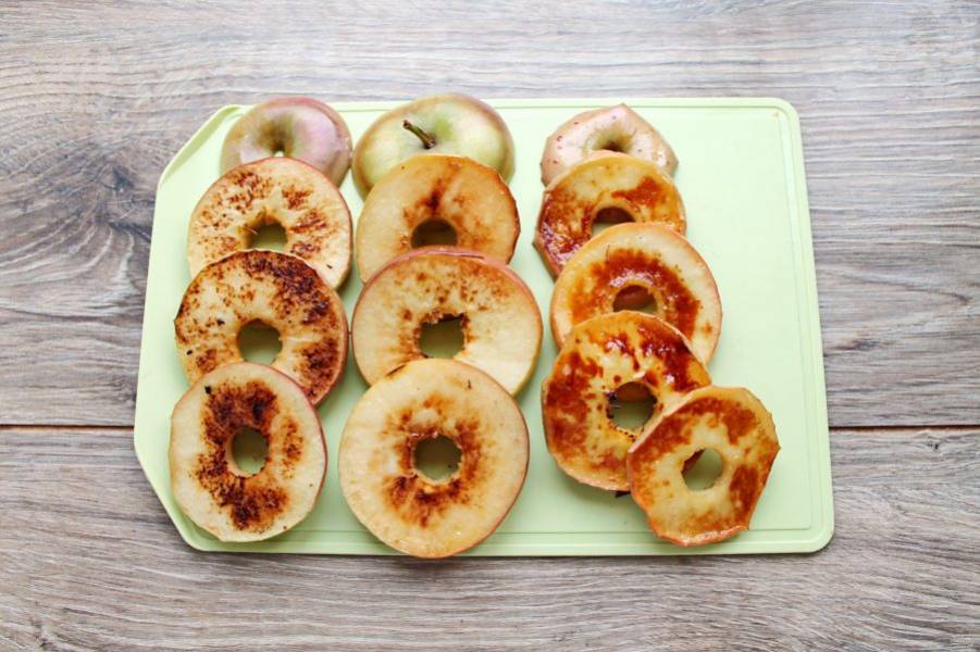 В сковороду налейте растительное масло и разогрейте на среднем огне. Выложите кружочки яблок и обжарьте до румяного состояния с двух сторон. Яблоки должны стать мягкими, но остаться целыми. Снимите со сковороды и остудите.