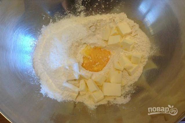 2. В миску просейте муку, добавьте тертую цедру одного лимона, соль, кубики сливочного масла и смесь из яиц и сахара.
