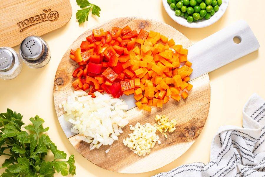 Нарежьте кубиками репчатый лук, морковь и болгарский перец. Чеснок и корень имбиря мелко порубите ножом.